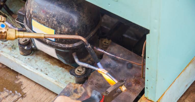 Manutenção técnica no compressor de uma geladeira